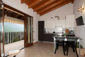 a kitchen with a dining table and a balcony at Panorama & Pisicna Lago Endine in Ranzanico