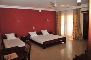 a bedroom with two beds and a red wall at HOTEL MENABE & Restaurant in Morondava +79 photos