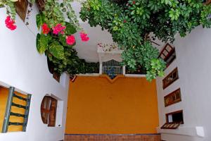 an orange door with flowers hanging from a building at JIBARI, riad luminoso con patio en la medina de Asilah in Asilah