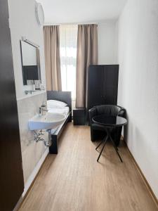a bathroom with a sink and a bed and a chair at Gästehaus E&E in Nierstein