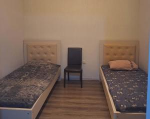 a bedroom with two beds and a chair at ბინა მახინჯაურში in Makhinjauri