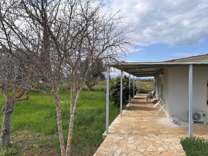 a porch of a building with a tree in a field at Nafplio Garden House in Nea Tiryntha
