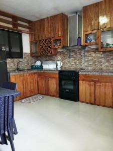 a kitchen with wooden cabinets and a black dishwasher at Villa Cresenciana in Batuan