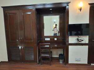 a man taking a picture of a cabinet with a mirror at Hotel Siris 18 in Gurgaon