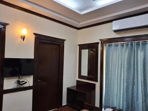 a room with a door and a tv and a window at Hotel Siris 18 in Gurgaon