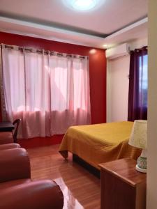 a bedroom with a bed with red walls and a couch at Villa Cresenciana in Batuan +48 photos