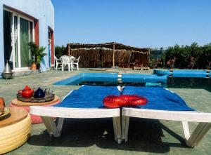 a table with two red pillows on it next to a pool at Blue Escape in Oulad Teïma