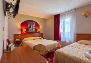a hotel room with two beds and a table at Hotel de L'Opéra in Bordeaux