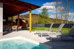 a patio with chairs and a table and a swimming pool at Bayerwald-Bungalow in Grattersdorf