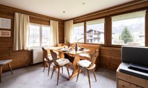 a dining room with a table and chairs and windows at Gästehaus Kaufmann in Mellau