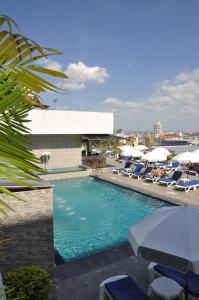 ein Swimmingpool mit Liegestühlen und Sonnenschirmen in der Unterkunft Flipper House Hotel - SHA Extra Plus in Pattaya