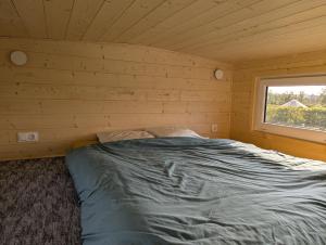 a bed in a wooden room with a window at Les Nids de Cerisy in Cerisy-la-Forêt