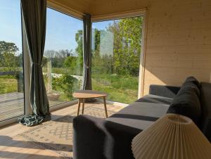 a living room with a couch and a large window at Les Nids de Cerisy in Cerisy-la-Forêt