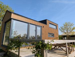 a modern house with glass windows and a wooden deck at Les Nids de Cerisy in Cerisy-la-Forêt