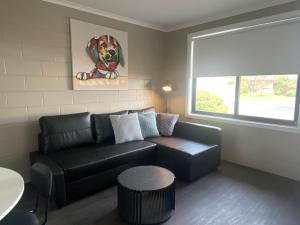 ein Wohnzimmer mit schwarzem Ledersofa und einem Fenster in der Unterkunft McInnes Units in Naracoorte