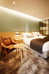 a hotel room with two beds and a chair and a table at MD HOTEL Dongtan in Hwaseong
