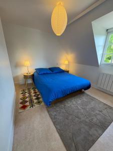 a bedroom with a blue bed with two lamps and a rug at Le Cottage in Cambremer