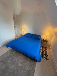 a large blue bed in a room with two lamps at Le Cottage in Cambremer