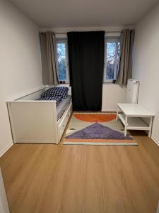 a bedroom with a bed and a table and two windows at Private Room in Oldenburg with Balcony in Shared Apartment in Hundsmühlerhöhe