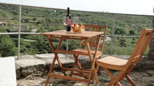 a table with a bottle of wine and two chairs at Casinha Das Portas in Castelo Bom