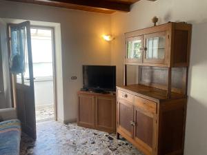a living room with a tv and a wooden cabinet at Casa nonna Bruna in Montebruno