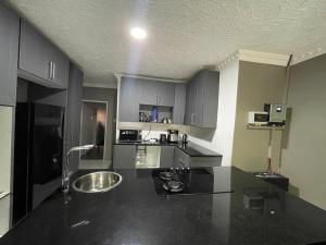 a kitchen with a black counter top with a sink at Alamaison in Umtali