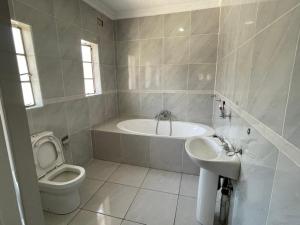 a white bathroom with a toilet and a sink at Alamaison in Umtali +12 photos