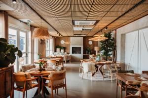 a restaurant with wooden tables and chairs and windows at Hotel De Zeeuwse Kust (family only) in Renesse