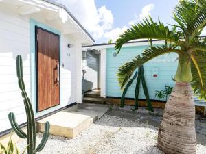 a house with a palm tree in front of a door at GuesthouseKAZE in Miyako-jima