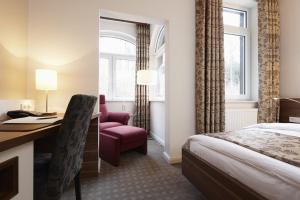 ビーレフェルトにあるBielefelder Berghotel zum Stillen Friedenのベッド、デスク、椅子が備わるホテルルームです。