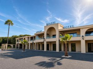 a hotel with two palm trees in front of it at Résidence Bozzi in Grosseto-Prugna