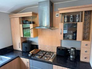 a kitchen with a stove top and a sink at Bag End, Near Porth Beach, Garden & Stream in Newquay Bay Resort