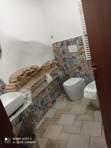 a bathroom with a toilet and a tiled wall at Casa Angelene in Vitorchiano