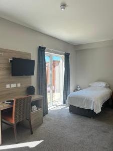a bedroom with a bed and a desk and a television at Riverstone Lodge Hotel in Perth
