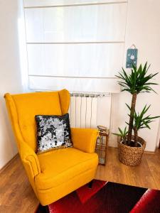 a yellow chair in a living room with a plant at Holiday Home Lungo Mare in Mlini
