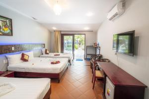 a hotel room with two beds and a table at Thai Hoa Mui Ne Resort in Mui Ne