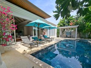 a woman sitting in chairs next to a swimming pool at Villa Desi in Bang Tao Beach