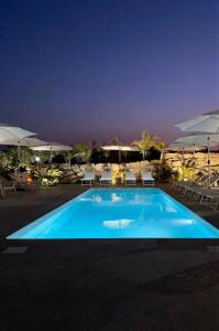 a swimming pool at night with chairs and umbrellas at Le tenute di punta bianca in Agrigento