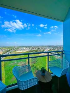 a balcony with two chairs and a table with a view at Nest & Rest Suites Azure North in San Fernando