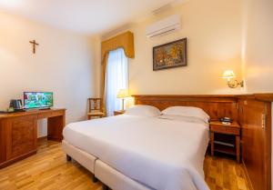 a bedroom with a large white bed and a television at Hosianum Palace in Rome
