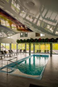 a large swimming pool in a building with chairs at Casa Elena - Resort & SPA in Voronet
