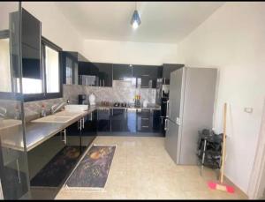 a large kitchen with black cabinets and stainless steel appliances at villa amani in Al Maqārisah