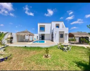 a large white house with a yard with a swimming pool at villa amani in Al Maqārisah