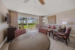 a living room with a table and chairs and a couch at Oceanfront Escape Pono Kai Resort A103 in Kapaa