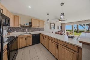 a large kitchen with wooden cabinets and a large window at Oceanfront Escape Pono Kai Resort A103 in Kapaa +46 photos