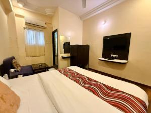 a hotel room with a large bed and a flat screen tv at Hotel New Sunder in Indore