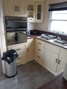 a kitchen with a sink and a stove top oven at Sea View Static Caravan With Decking - Skipsea Sands Holiday Park in Skipsea +4 photos