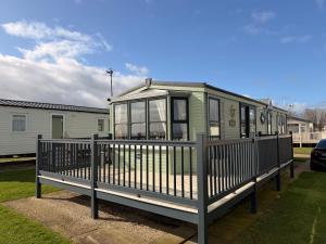 a green tiny house with a wooden deck at Sea View Static Caravan With Decking - Skipsea Sands Holiday Park in Skipsea