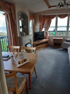 a living room with a table and a tv at Sea View Static Caravan With Decking - Skipsea Sands Holiday Park in Skipsea