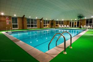 a large swimming pool in a building with a green floor at Wensum Valley Hotel Golf and Country Club in Norwich